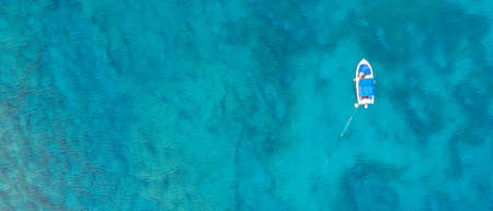 A high angle panoramic shot of a boat in the middle of the ocean