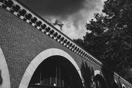 A low angle grey scale shot of a brick bridge near some trees captured in Paris, France