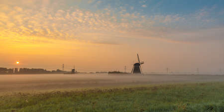 A beautiful shot of mills in the field with the sun rising in the backgroundの写真素材
