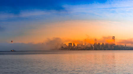 The sun setting over the city the ocean shore giving the sky a warm lookの写真素材