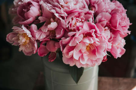 A closeup shot of beautiful pink peonies in a plastic vase on blurred background