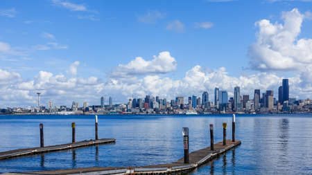 A wooden pier over a sea with the city of Seattle, USA under the beautiful clouds in the backgroundの写真素材