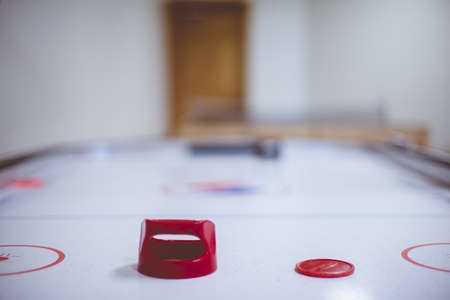 A closeup shot of an air hockey table with the red puck and a blurred backgroundの写真素材