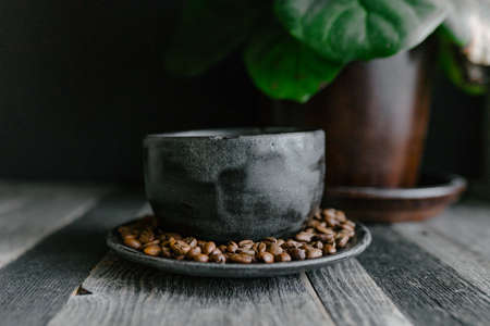 A closeup shot of coffee beans on a clay plate on a wooden tableの写真素材