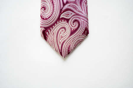 An overhead shot of a dark purple tie with patterns on a white surface