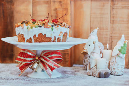 A closeup shot of a delicious fruitcake with white cream ion a Christmas table