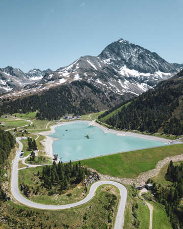 A high angle shot of a lake surrounded by tree covered hill with a mountain in the backgroundの写真素材