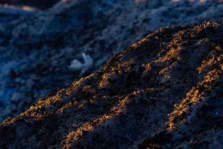 A closeup shot of a muddy and frozen rocky hill with a blurred background