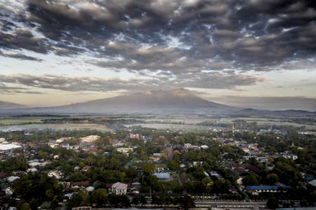 An overhead shot of city buildings with a mountain in the distance under a cloudy skyの写真素材