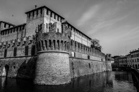 A beautiful shot of a castle near the water and buildings in black and white