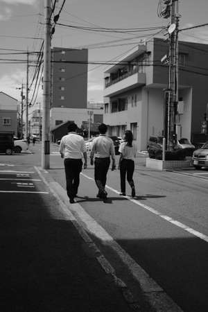 MATSUYAMA, JAPAN - Sep 14, 2019: A vertical greyscale shot of three friends walking along the street during daytimeのeditorial素材