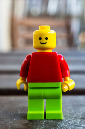 POZNAN, POLAND - Jul 04, 2020: Lego figurine with happy expression and red with green clothes on a wooden surfaceのeditorial素材