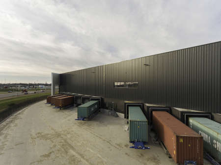 OOSTERHOUT, NETHERLANDS - Dec 06, 2019: Trailers with containers in front of a warehouse. Ready for...