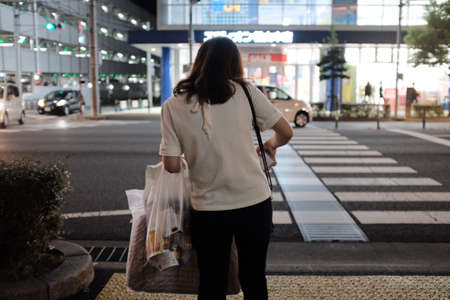 MATSUYAMA, JAPAN - Sep 15, 2019: A horizontal shot of a female with shopping bags in the street at nightのeditorial素材