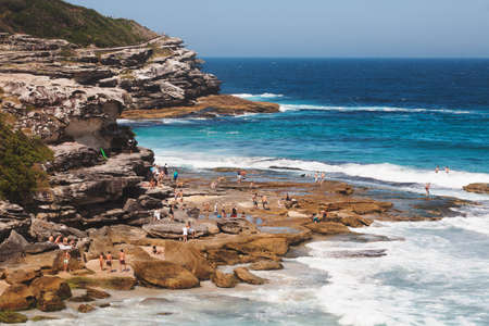 SYDNEY, AUSTRALIA - Dec 23, 2012: Crowds of tourists relaxing and sunbathing by a  cliff in Tamarama beach in a sunny afternoon of summer. Sydnay, Australiaのeditorial素材