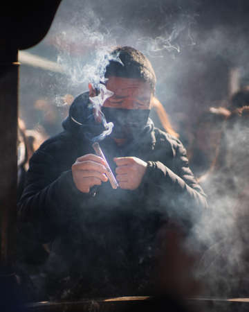 TOKYO, JAPAN - Feb 19, 2020: A man prays at the Jokoro in Senso-ji temple, Asakusa, Japan. 1 of 3