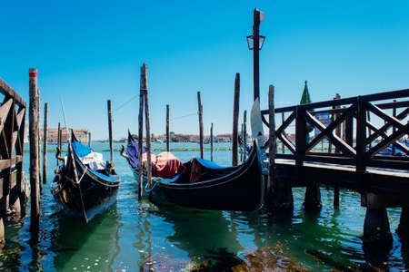 VENICE, ITALY - Jun 20, 2018: A beautiful shot of gondolas parked next to a pier in Venice, Italyのeditorial素材