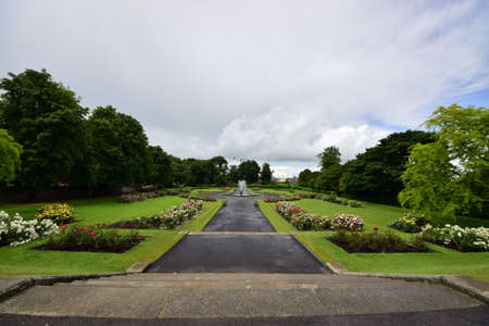 The Kilkenny castle garden surrounded by greenery under a cloudy sky in Irelandのeditorial素材