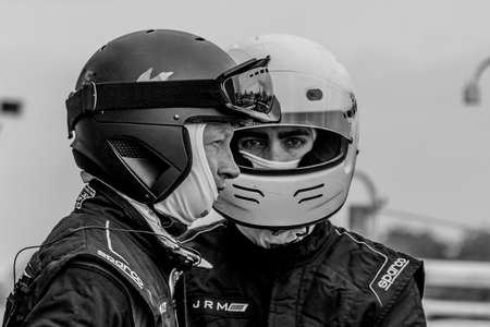 DERBY, UNITED KINGDOM - Dec 01, 2019: Race drivers facing two different directions. One may be a race driver and the other pit crew. I just liked the timing and the black & white helmets.のeditorial素材