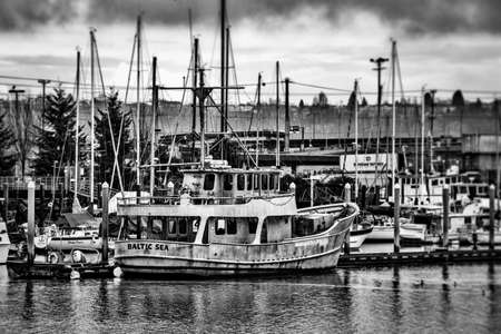 A gray scale shot of boats on the sea near the dock with the cloudy sky in the backgroundのeditorial素材