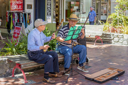 WELLINGTON, NEW ZEALAND - Jan 27, 2015: Two old street musicians sitting on a bench in the streets of Wellington and playing instrumentsのeditorial素材