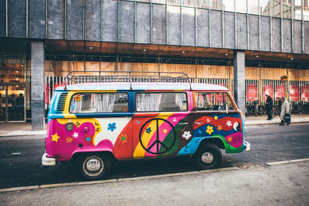 A wide shot of a multi-color van parked on a roadside near a buildingのeditorial素材