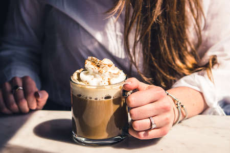 A frappe coffee in a glass mug  with whipped cream on topの写真素材