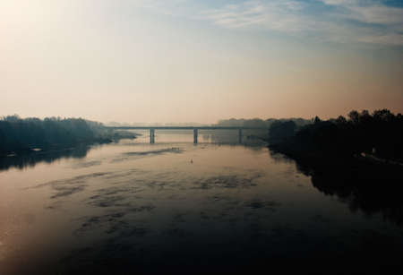 An aerial shot of a bridge going over the river surrounded by trees