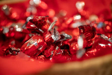 A closeup shot of a bowl of candies wrapped in festive wrappingの写真素材
