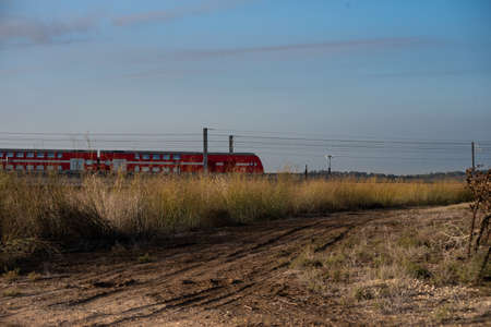 A train on a railway surrounded by greenery under a blue cloudy sky during the evening
