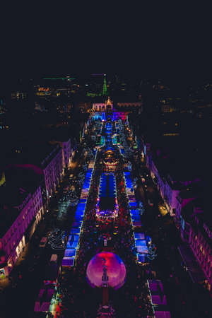 A wide angle shot of lit up buildings in a city full of people at nightの写真素材