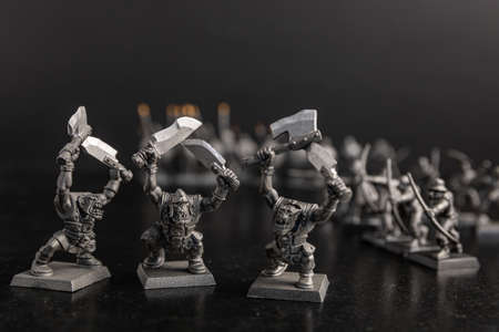 A grayscale selective focus shot of creatures holding swords figurinesの写真素材