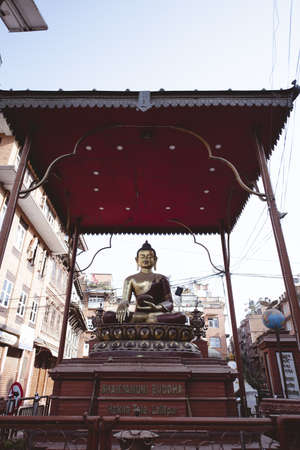 A vertical shot of the Buddha statue in the middle of buildingsのeditorial素材
