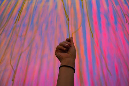 A hand reaches up to grab a colored string.の写真素材