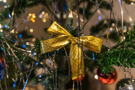 A selective focus shot of a golden bow and ornaments on a Christmas treeの写真素材