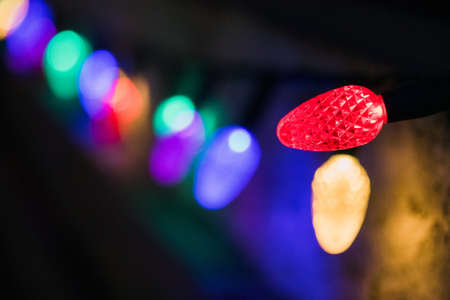A selective focus shot of colorful Christmas lights in a dark room