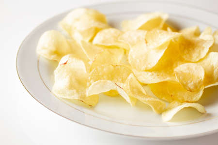 A closeup shot of homemade chips on a white plate on a white surface