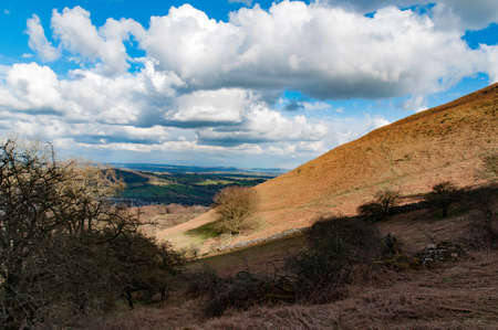Welsh hillside looking out on a valley with cloudy blue sky