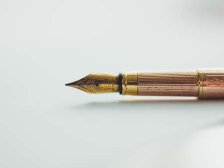 A closeup shot of a vintage golden ink pen on a white surfaceの写真素材
