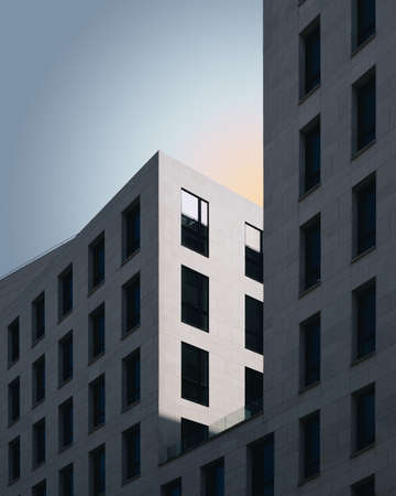 A vertical shot of a grey concrete building under the blue sky