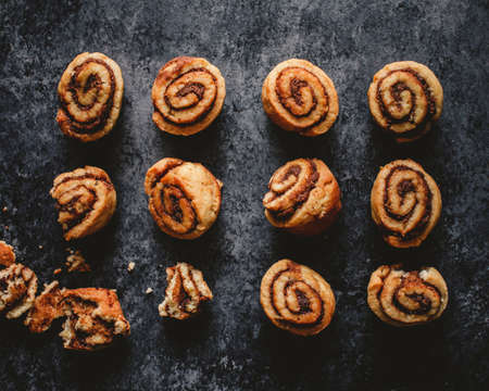 A lot of freshly baked delicious cinnamon rolls on a black surfaceの写真素材