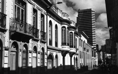 A grey scale shot of beautiful buildings on a paved street under the cloudy skyの写真素材
