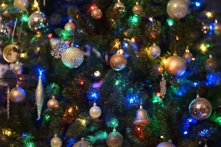 A Christmas tree decorated with lights and toys against a blurry background