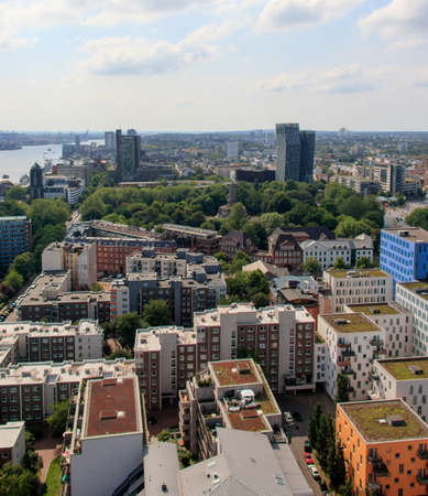 A high angle shot of a lot of buildings surrounded by green trees under the cloudy skyの写真素材