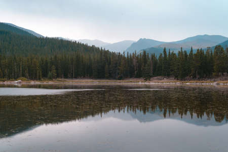 A beautiful shot of a lake reflecting the trees on the shore under a blue sky