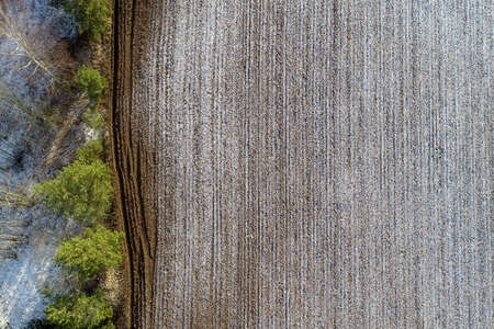 An overhead shot of an agricultural field with drops of snow in the countryside