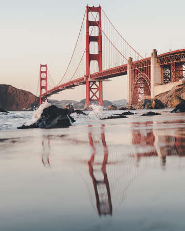 A vertical shot of the golden gate bridge under a cloudy sky