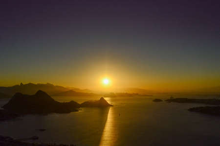 A breathtaking view of the sunset over the calm ocean surrounded by mountains