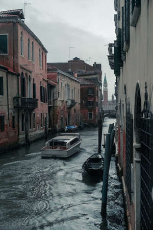 A vertical shot of scenery of boats sailing in the canals of historic Veniceの写真素材