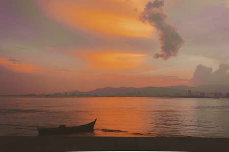 A single boat in the sea with the beautiful sunset reflecting on a water surfaceの写真素材